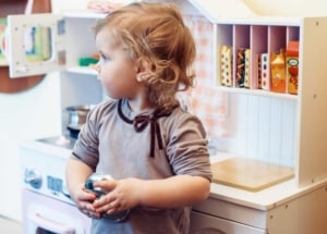 Kind an einer Spielküche aus Holz im Landhausstil (depositphotos.com)